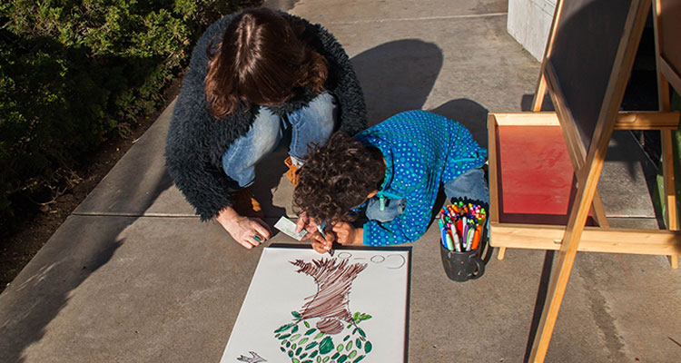 two people coloring on a sidewalk
