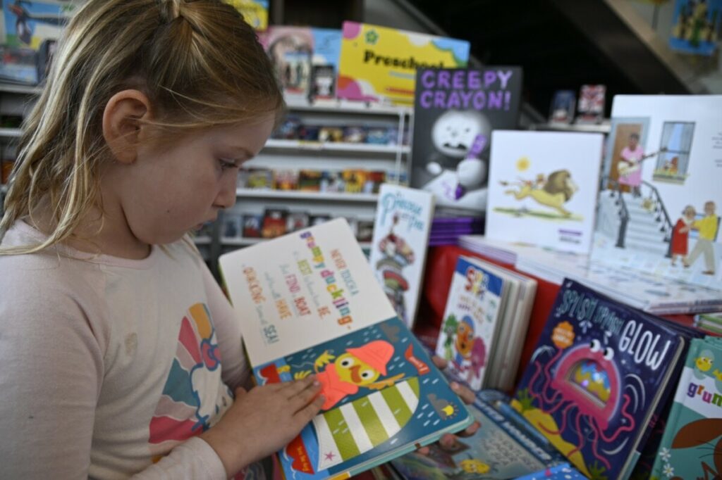 a San Diego Cooperative tuition-free charter school student reading a book in front of a book display