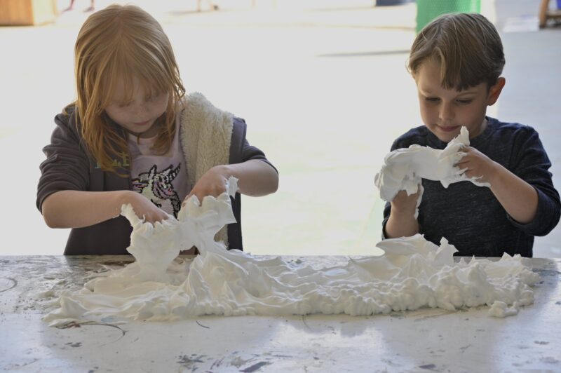 two students at San Diego Cooperative tuition-free TK-8 charter school work together on a shaving cream art sculpture.